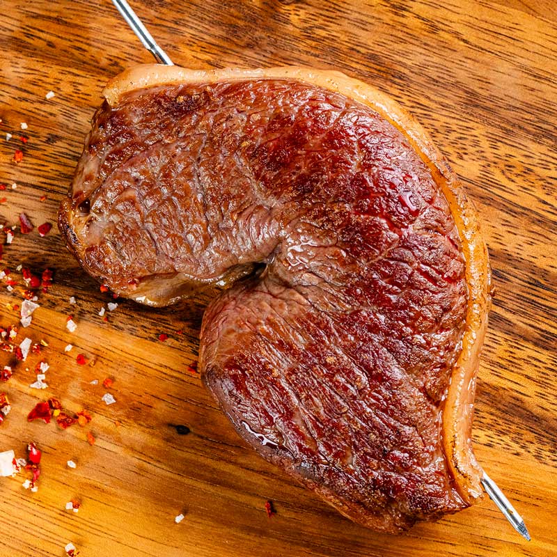 Am Spieß gegrilltes Picanha von TAURBULL, Premium Black Angus Tafelspitz, knusprige Kruste und zartrosa Kern.