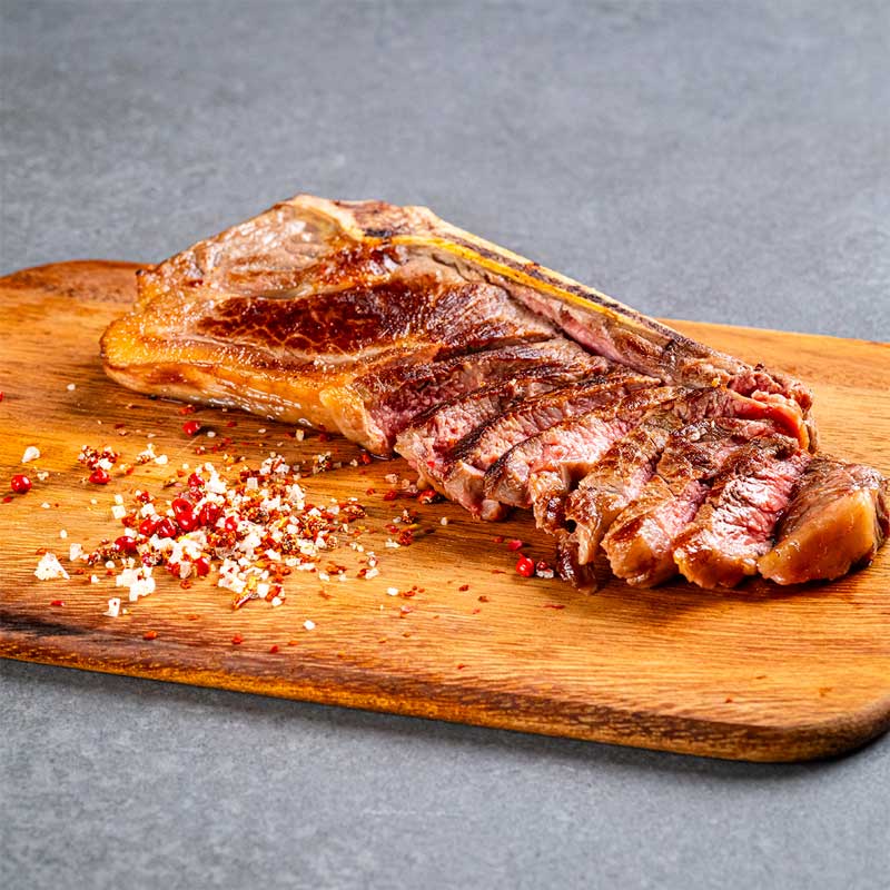 Premium Black Angus Sirloin Steak von TAURBULL, perfekt gegrillt, saftig und kräftig im Geschmack, aufgeschnitten in Scheiben auf Holzbrett.