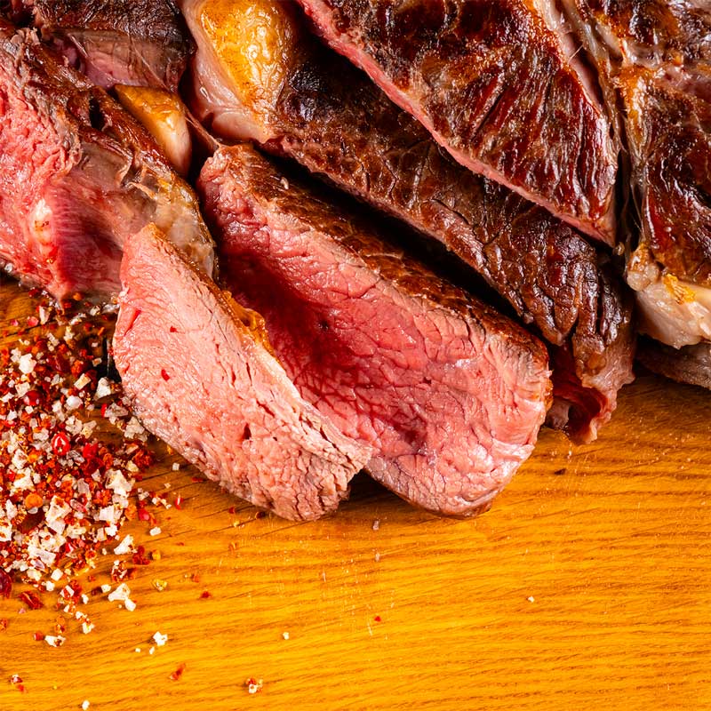 Tomahawk Steak von TAURBULL, Premium Black Angus Steak, nahaufnahme, Kruste und zart rosa saftiger Kern, gegrillt