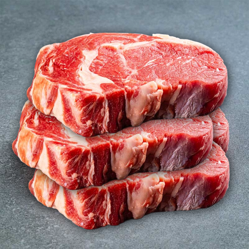 Mehrere rohe Rindersteaks mit Knochen auf grauem Hintergrund.